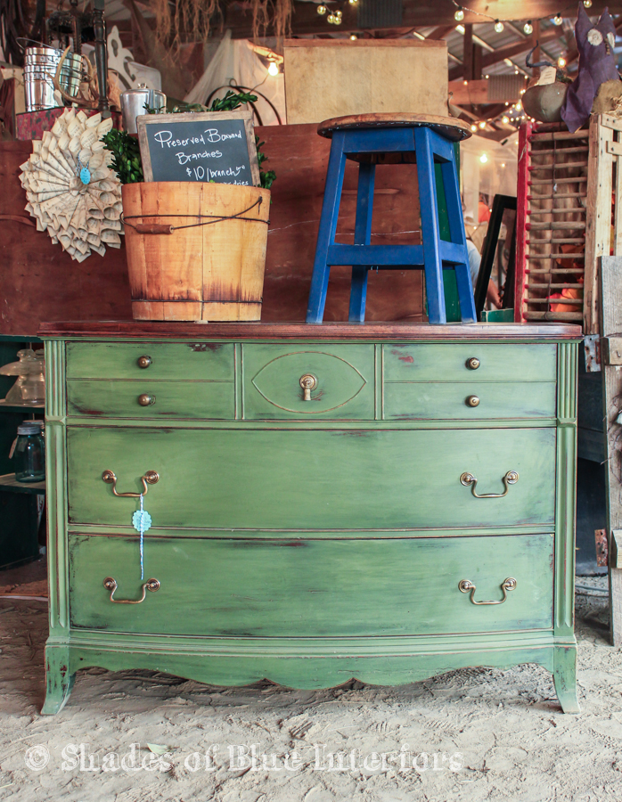 Green dresser with blue stool on top and bucket with preserved boxwood inside.