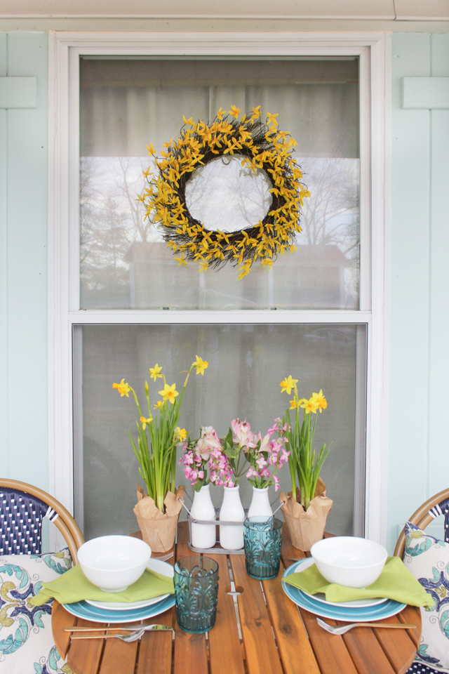 Forsythia wreath hung on outdoor window above table and chairs
