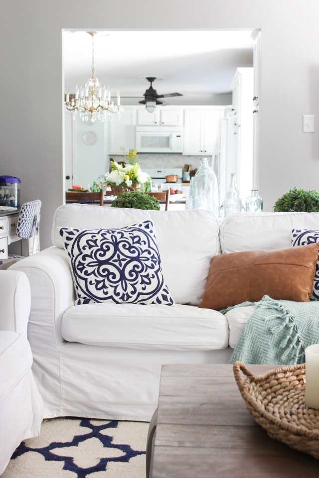 White sofa with navy and white pillow, and camel leather pillow- summer living room