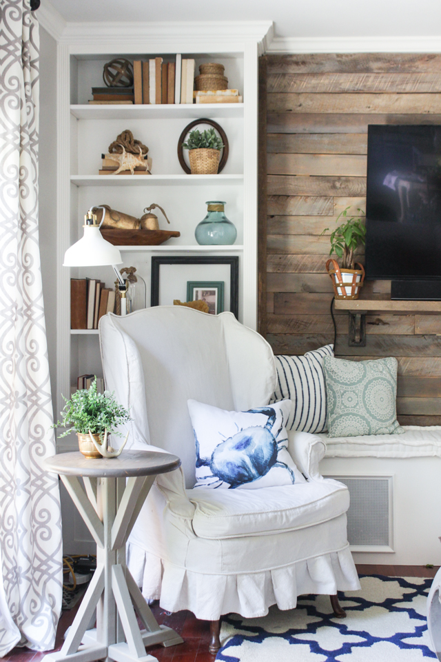 Pallet accent wall, built-in bookcase, and slipcovered wing chair