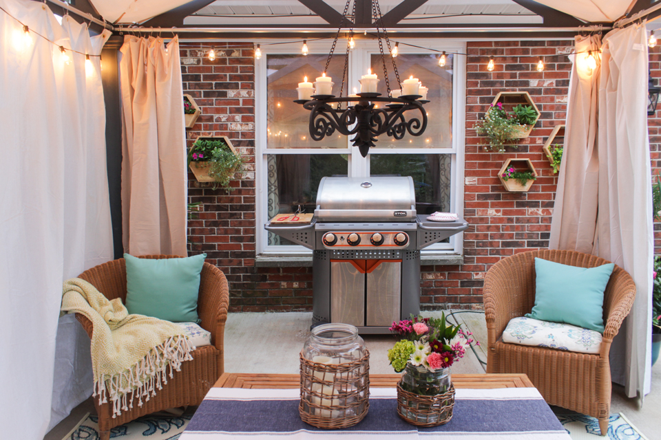 Decorative hex planters on brick, Stok grill, candle chandelier, wicker chairs, canvas curtains