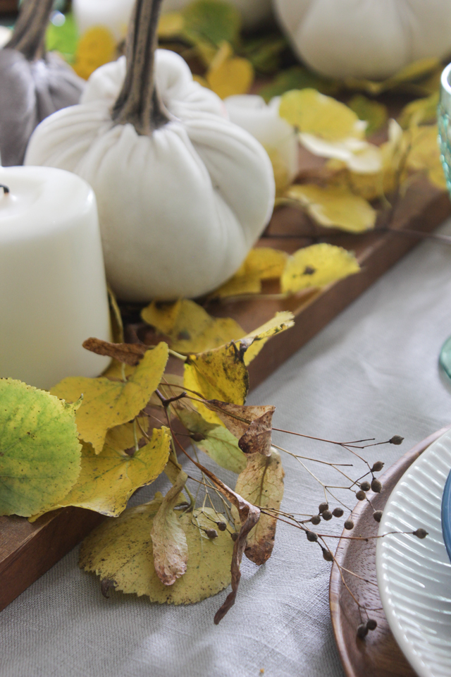 Fall centerpiece with fall leaves, velvet pumpkins, and pillar candles on wooden tray
