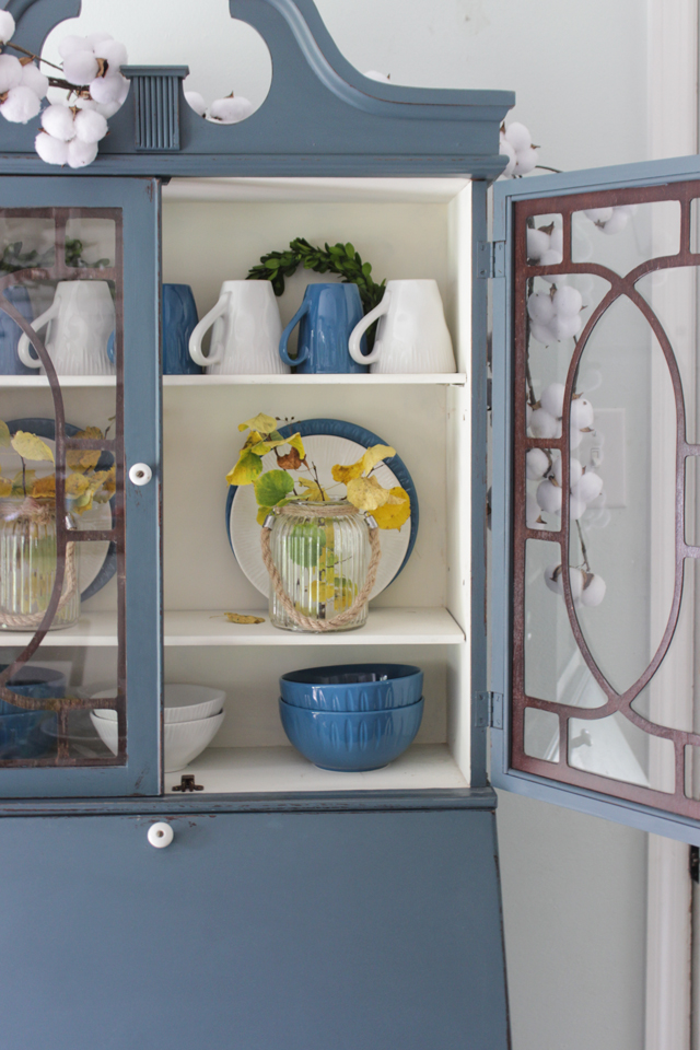Blue cabinet with blue and white dishes, fall leaves, cotton stems
