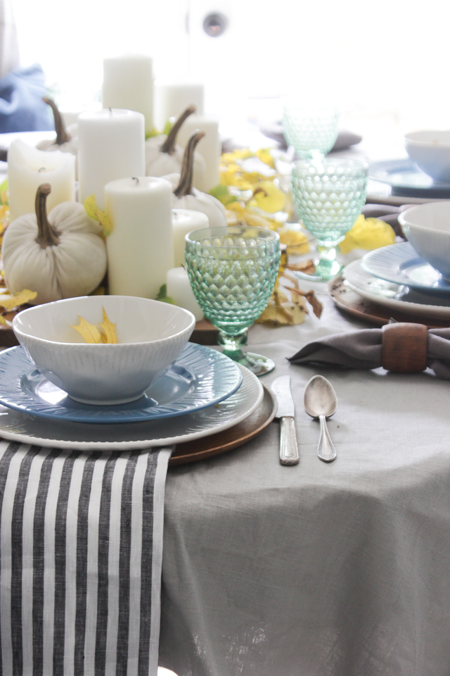 Fall tablescape with pillar candles, pumpkins, and striped napkin