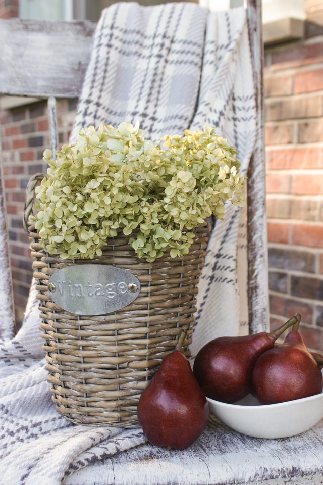 Vintage wicker basket, dried hydrangeas, red pears, and gray flannel throw