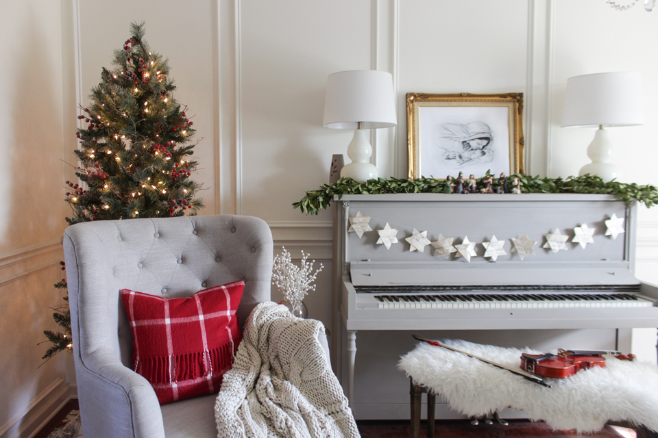 Corner Christmas tree, wing chair, and gray piano with garland