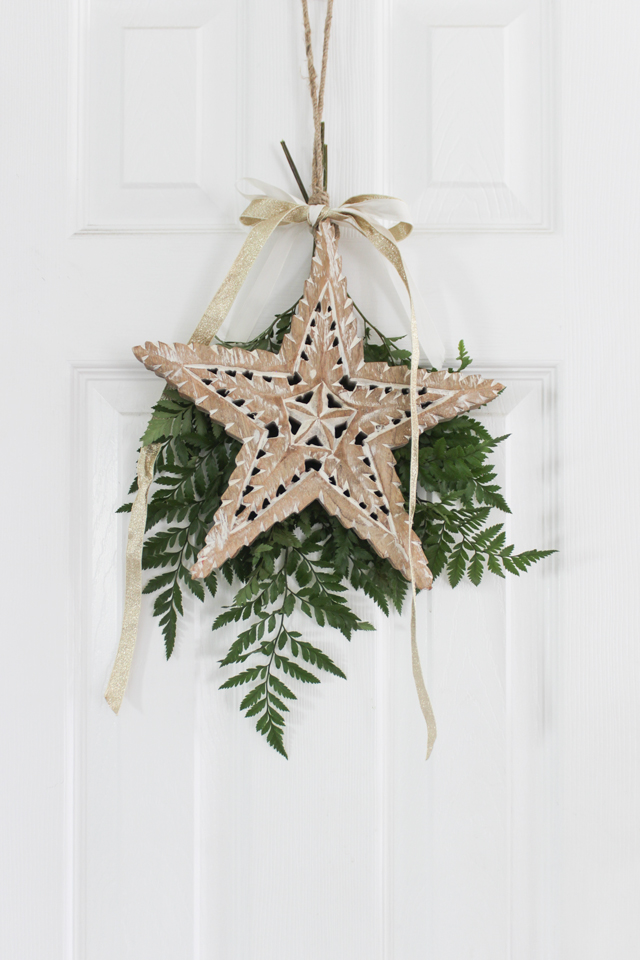 Christmas wooden star and fresh greens hanging on interior door