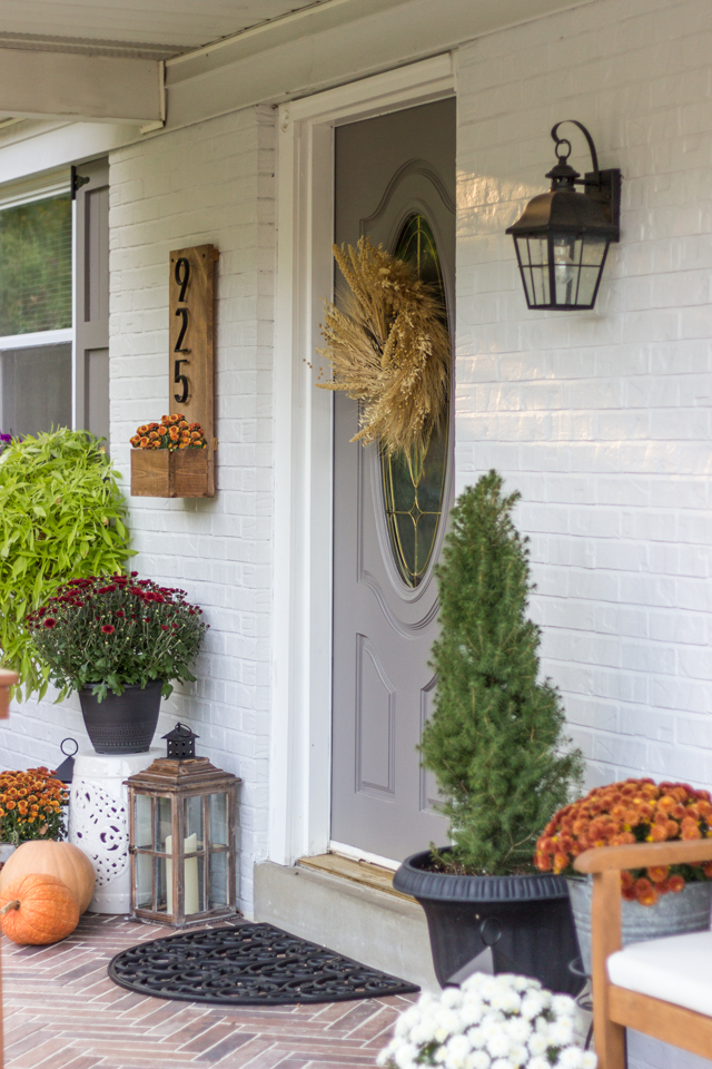 Fall front door with mums, pumpkins and lanterns. 