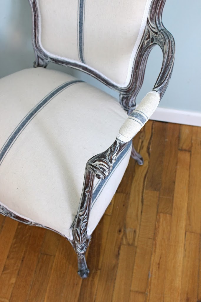 White washed frame of french chair, reupholstered with grain sack fabric and white trim