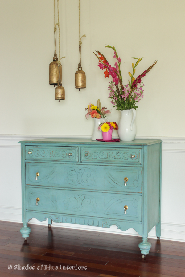 Turquoise dresser staged with tropical florals and hanging bells