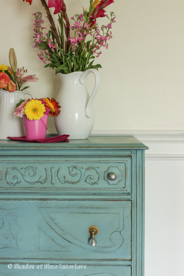 Turquoise dresser staged with tropical florals and hanging bells