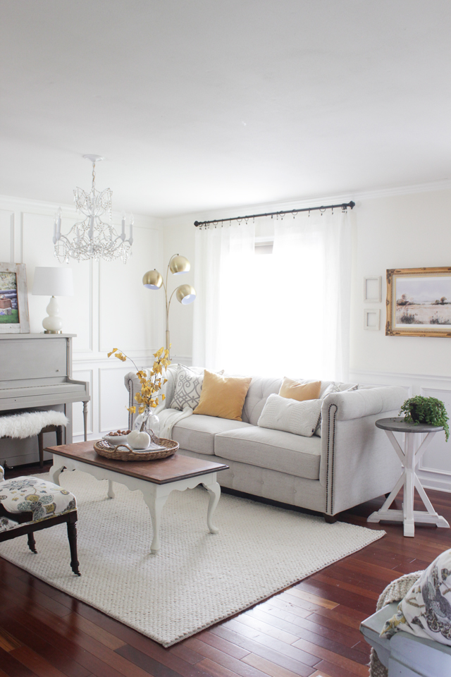 Gray painted piano, tufted couch, and yellow fall accents